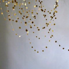 gold confetti hanging from the ceiling in front of a white wall and chair