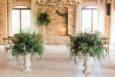 two vases filled with plants on top of a white tile floor next to windows