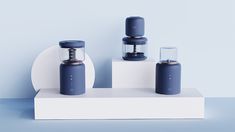 three different blenders sitting on top of a white stand with blue walls in the background