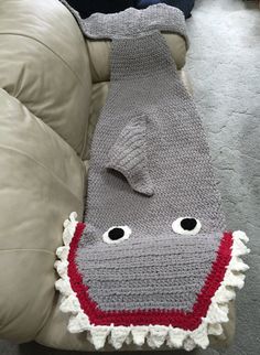 a crocheted hippo laying on top of a couch covered in a blanket