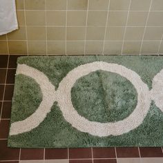 a bathroom rug with the word zoo painted on it in white and green colors next to a toilet