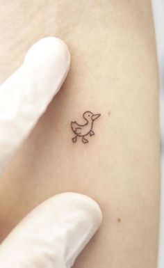 a small bird tattoo on the back of a woman's left arm