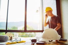 a construction worker talking on the phone while standing in front of a window with his work tools