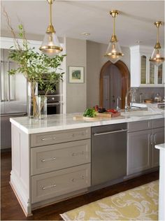 a large kitchen with an island in the middle and gold lights hanging from the ceiling