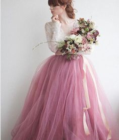 a woman in a pink dress with flowers on her head is standing against a white wall