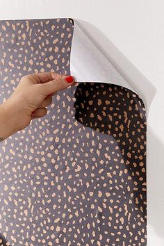 a hand is holding a piece of paper over an animal print pattern on the wall