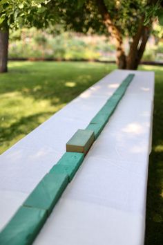 a long white table with green tape on it in the middle of a park area