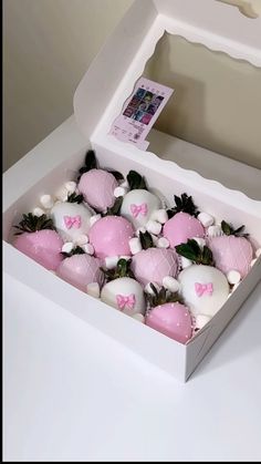 a box filled with pink and white chocolate covered strawberries on top of a table