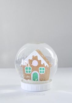 a snow globe with a ginger house in it on top of a white countertop