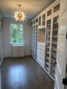 an empty walk - in closet with lots of shelves and drawers on the wall, next to a window