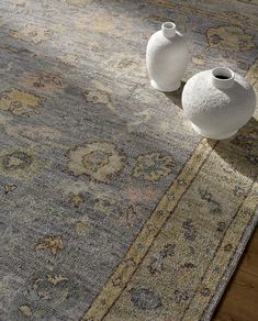 two white vases sitting on top of a rug