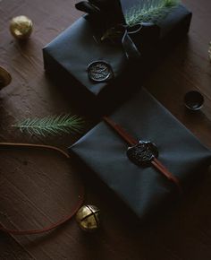 two wrapped presents sitting on top of a wooden table next to christmas ornaments and pine cones