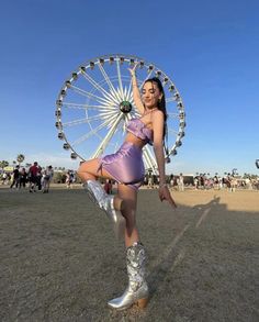 a woman in a short skirt and cowboy boots posing with a ferris wheel behind her