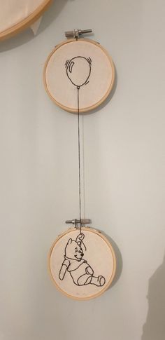 two embroidery hoop hanging on the wall with an image of a baby holding a balloon