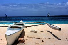 a boat on the beach with sailboats in the background