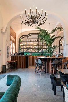 a restaurant with tables, chairs and plants in the middle of the room is lit by chandelier lights