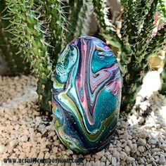 an egg sitting on top of a gravel covered ground next to a green cactus plant