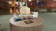 a table topped with pictures and flowers on top of a carpeted dance floor next to a chandelier