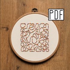 a cross stitch pattern with the word love spelled out in beads on a wooden hoop