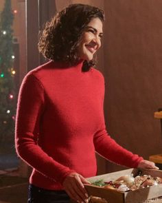 a woman in a red sweater holding a box of food