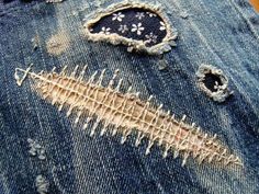 an old pair of jeans with holes in the back and sides that have been stitched together