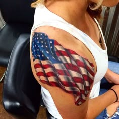 a woman with an american flag tattoo on her arm and shoulder, sitting in a chair