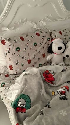 two stuffed animals sitting on top of a bed covered in white sheets and blankets with cartoon characters