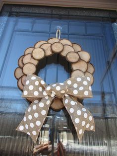 a wreath made out of wood with polka dots on it and a bow hanging from the front door