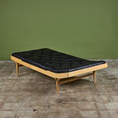 a black leather mattress sitting on top of a tile floor next to a green wall