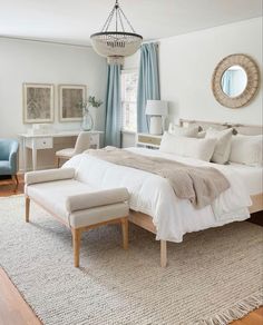 a bedroom with a large bed, chair and ottoman in front of a mirror on the wall