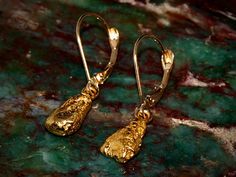 A beautiful pair of dangle earring made from natural gold nuggets that were found in Alaska. All components used (hooks, wire, jump rings) are 14k gold, and the nuggets are natural placer gold nugget from Alaska so they generally average about 22k in purity. These earrings measure approximately 28mm from the top bend in the hook to the bottom of the gold nugget. The nuggets themselves are about 10mm long. They weigh 4.05 grams combined. All of the gold nuggets I sell are ethically sourced by loc Elegant Gold Nugget Earrings, Gold Nugget Earrings As Gift, Yellow Gold Nugget Brass Jewelry, Gold Hand Forged Drop Earrings, Hand Forged Gold Drop Earrings, Hammered Yellow Gold Long Drop Jewelry, Polished Yellow Gold Nugget Jewelry, Hand Forged Yellow Gold Dangle Earrings, Nugget Jewelry