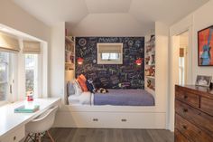 a bedroom with chalkboard on the wall and a bed next to it in front of a window