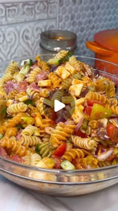 a glass bowl filled with pasta salad on top of a table