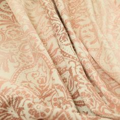 an orange and white paisley print fabric on top of a bed sheet with no sheets