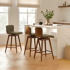 three stools sit in front of a kitchen island with marble counter tops and white walls