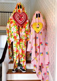 two children's bathrobes with hearts and flowers on them sitting on the stairs