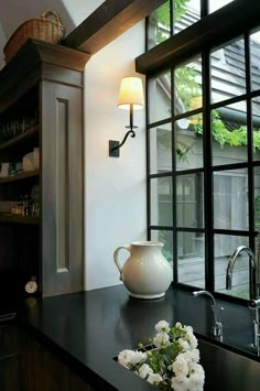 a white vase sitting on top of a counter next to a window with glass panes