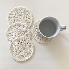 four crocheted coasters and a cup of coffee on a white table top