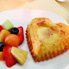 a heart shaped pastry next to fruit on a plate