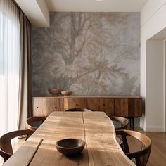 a wooden table with two bowls on it in front of a large wallpapered tree