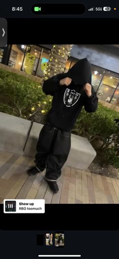 a young boy wearing a black hoodie and standing in front of a building