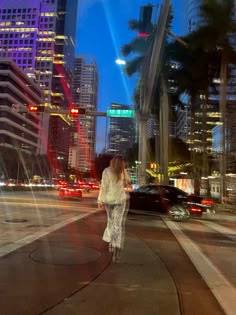 a woman is walking down the street at night