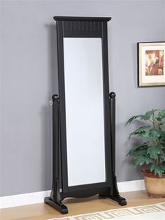 a tall black standing mirror on top of a wooden floor next to a potted plant