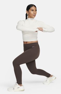 A snug fit and long sleeves with thumbhole cuffs add to the sporty vibe of this funnel-neck top made with the brand's Dri-FIT sweat-wicking technology. Funnel neck Long sleeves with thumbhole cuffs Dri-FIT moisture-wicking technology 80% nylon, 20% spandex Machine wash, dry flat Imported High Neck Athleisure Activewear For Gym, Athleisure High Neck Activewear For Yoga, Athleisure High Neck Yoga Activewear, High Neck Athleisure Activewear For Yoga, Nike Activewear For Fall Running, Nike Fitted Activewear For Fall, Nike Fall Running Activewear, Nike White Long Sleeve Activewear, White Nike Long Sleeve Activewear