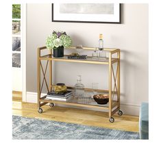 a gold metal and glass bar cart with drinks on it in a living room setting