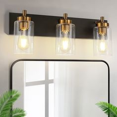 a bathroom vanity with three lights and a mirror in front of the light fixture on the wall