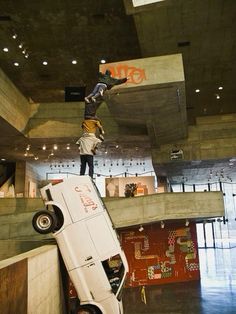 a skateboarder is doing tricks on the side of a car in a building