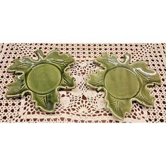 two green ceramic turtle coasters sitting on top of a lace doily covered table