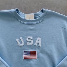 This very soft, unique and comfy USA crewneck sweatshirt is perfect to lounge around anywhere in cool beach weather or cozy fall weather! This is also perfect to wear for 4th of July! It is also a great gift to your loved ones of any gender! - All our sweatshirts run a UNISEX fit. They are naturally oversized, but if you want a more baggy look then size up! - These letters are iron-on patched and is heat pressed, not embroidered. - Material is super soft and comfy! ♡ - Please note that crewneck Cozy Blue Top With Letter Print, Fall Crew Neck Tops Made In Usa, Usa Crewneck, Embroidered Material, Beach Weather, Usa Sweatshirt, Usa Shirt, Embroidered Sweatshirt, Fall Weather