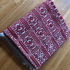 a red and white blanket laying on top of a wooden floor